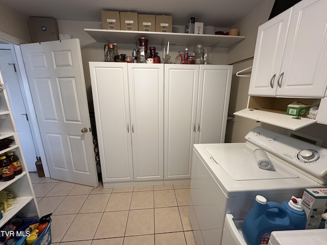 clothes washing area featuring light tile patterned floors, washer and dryer, and cabinet space