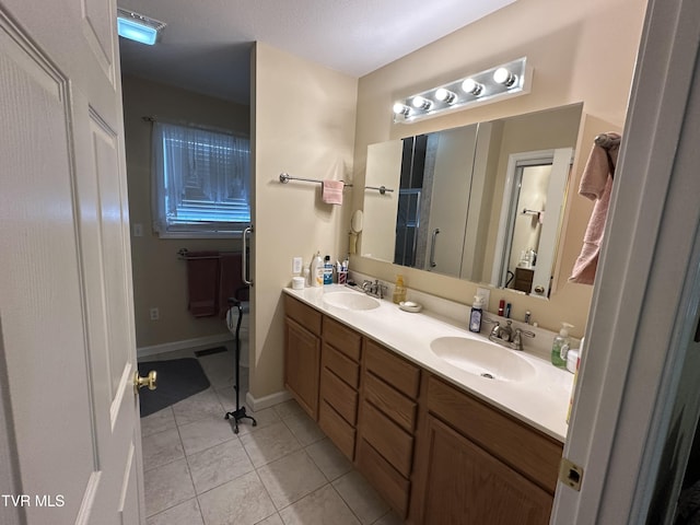 full bath with a sink, baseboards, double vanity, and tile patterned flooring