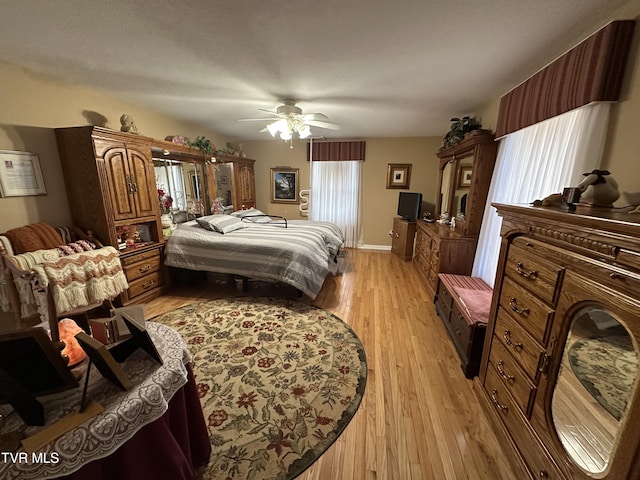 bedroom with light wood-style floors, baseboards, and ceiling fan