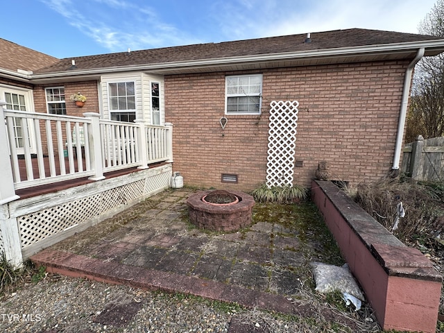 back of property featuring crawl space, a fire pit, brick siding, and a patio area