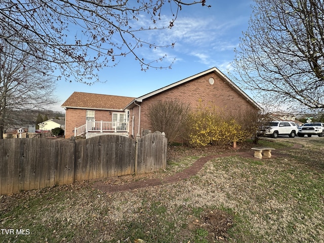 view of side of property featuring brick siding and fence