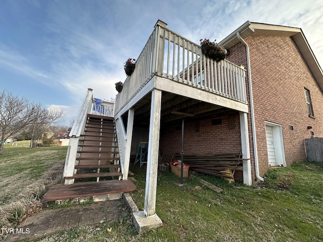 view of side of property featuring a deck, stairway, a yard, and brick siding