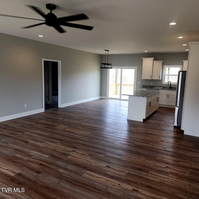 kitchen with freestanding refrigerator, a sink, ceiling fan, white cabinets, and open floor plan