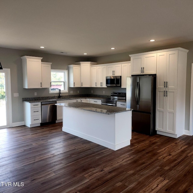 kitchen featuring white cabinetry, dark wood-type flooring, appliances with stainless steel finishes, and a kitchen island