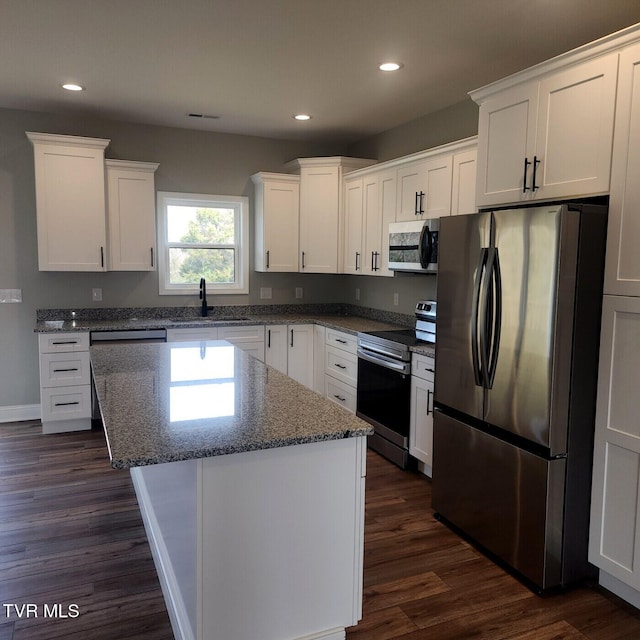 kitchen with a sink, a kitchen island, appliances with stainless steel finishes, and white cabinetry