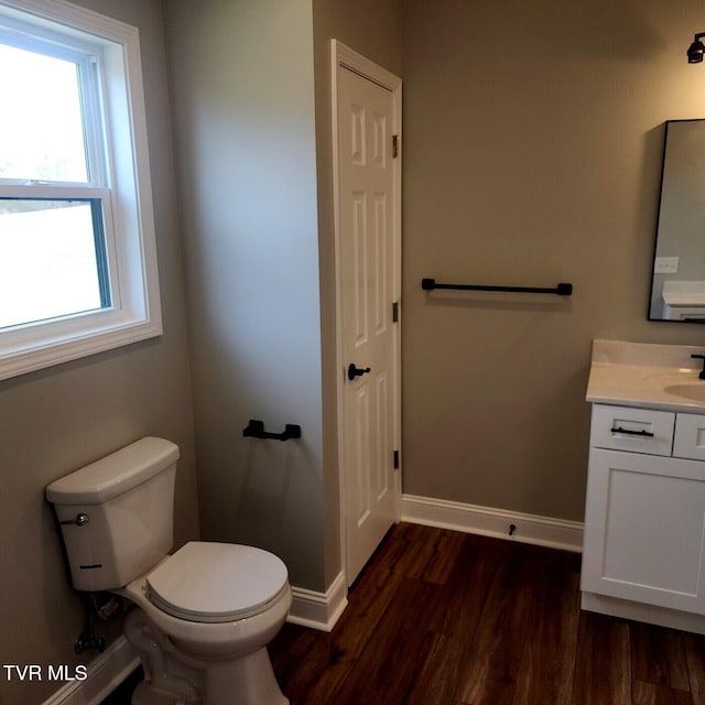 bathroom featuring toilet, vanity, baseboards, and wood finished floors