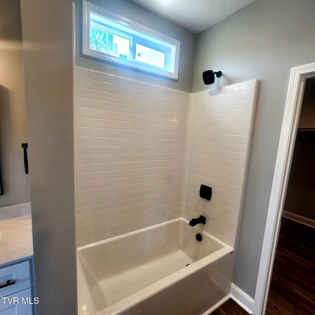 bathroom featuring wood finished floors, shower / washtub combination, vanity, baseboards, and a spacious closet