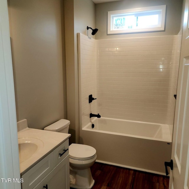 bathroom featuring vanity, toilet, wood finished floors, and shower / washtub combination