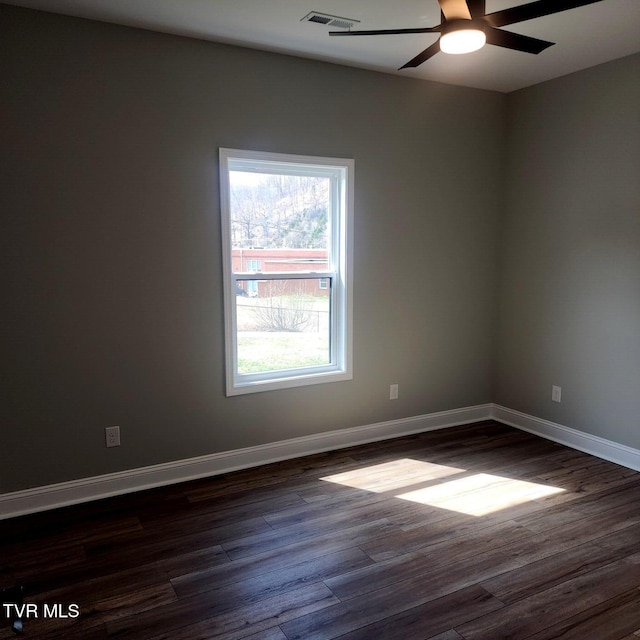 spare room with dark wood-style floors, visible vents, and baseboards