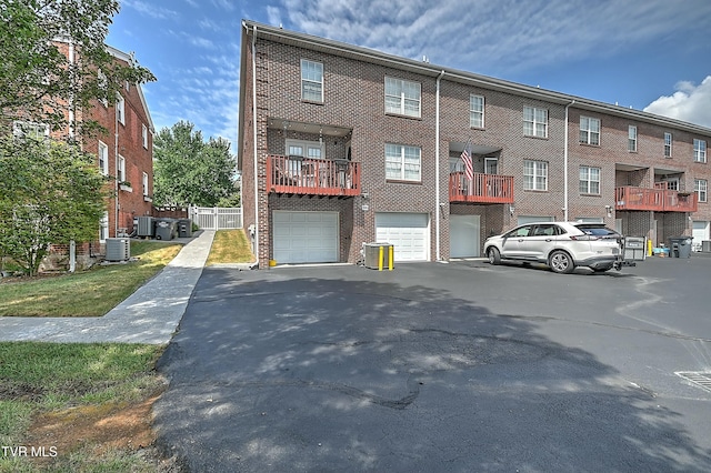 exterior space featuring central air condition unit, brick siding, a garage, and driveway