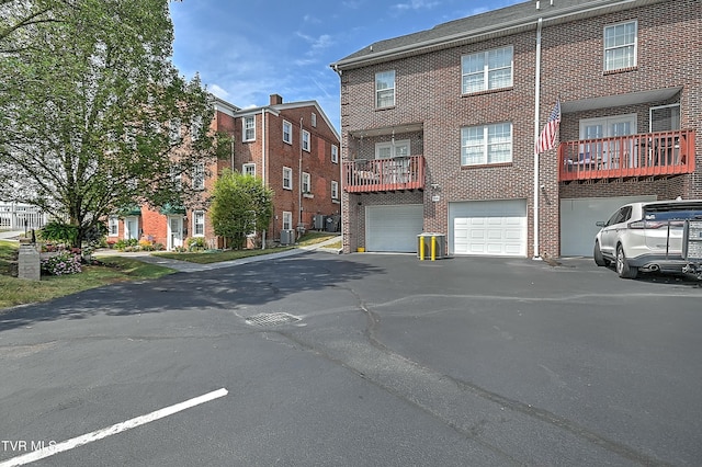 rear view of house featuring brick siding, central air condition unit, an attached garage, and driveway