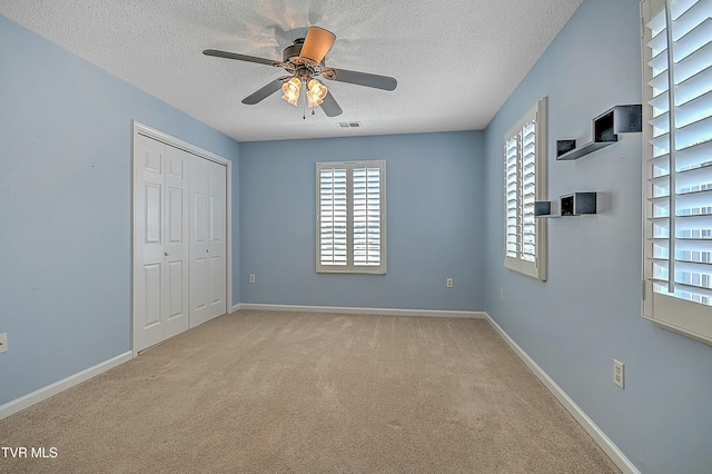 unfurnished bedroom with carpet flooring, baseboards, a closet, and a textured ceiling