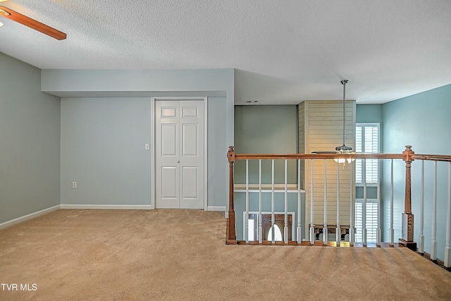 interior space with carpet, a ceiling fan, baseboards, and a textured ceiling