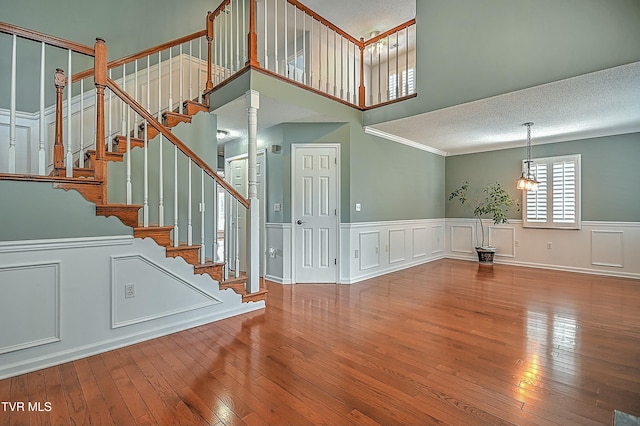 interior space with a decorative wall, wood-type flooring, a textured ceiling, and ornate columns