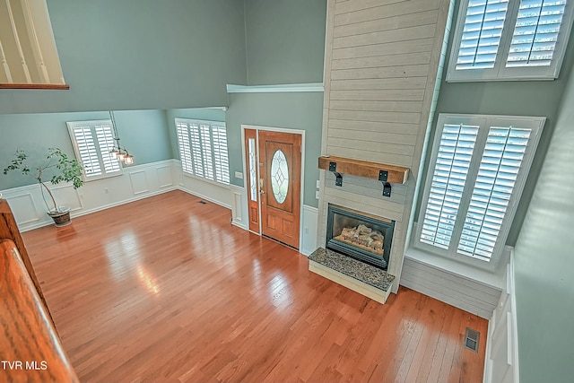 foyer with visible vents, a fireplace, a high ceiling, and wood finished floors