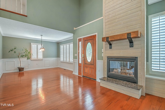 foyer featuring a large fireplace, a textured ceiling, hardwood / wood-style floors, and ornamental molding