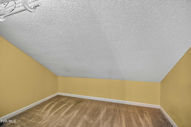 additional living space featuring lofted ceiling, carpet flooring, baseboards, and a textured ceiling