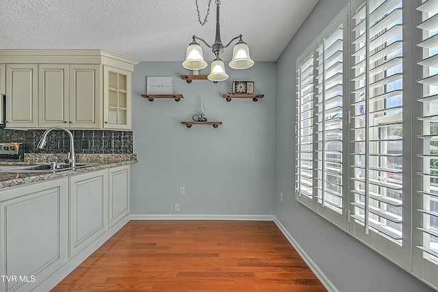 unfurnished dining area featuring a notable chandelier, plenty of natural light, wood finished floors, and a sink