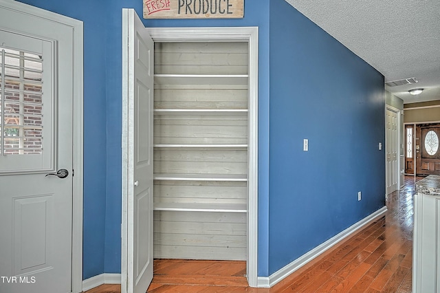 interior space with visible vents, baseboards, a textured ceiling, and wood finished floors