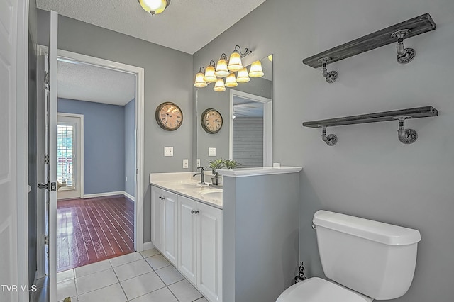 bathroom with tile patterned floors, toilet, a sink, a textured ceiling, and baseboards