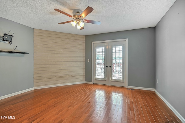 unfurnished room featuring french doors, a textured ceiling, ceiling fan, and hardwood / wood-style flooring