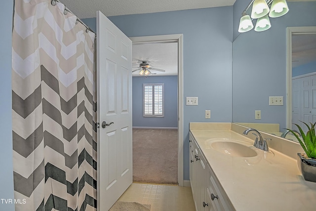 full bathroom featuring a shower with curtain, a ceiling fan, a textured ceiling, baseboards, and vanity