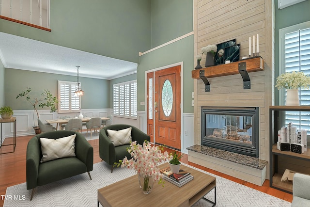 living area with wainscoting, an inviting chandelier, wood finished floors, and a fireplace