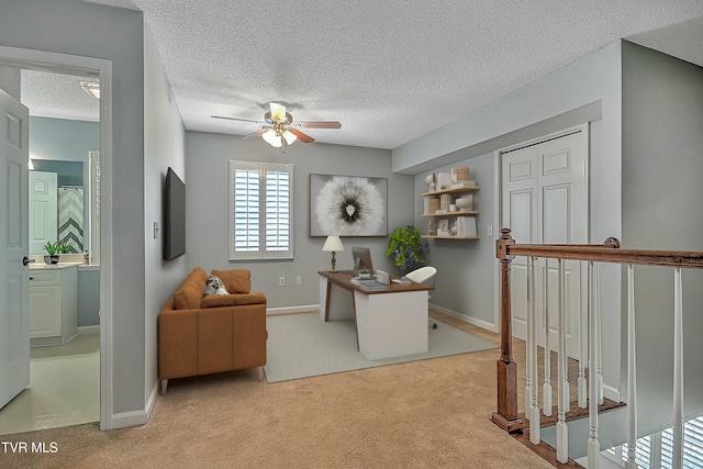 office featuring baseboards, carpet, a ceiling fan, and a textured ceiling