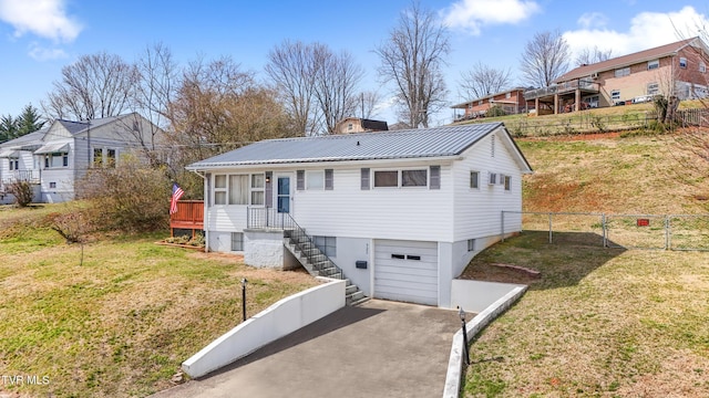 view of front of property featuring metal roof, a front yard, an attached garage, and fence