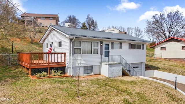 view of front of home with fence, a front yard, a chimney, metal roof, and a garage