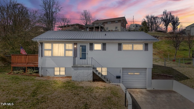 view of front facade featuring fence, concrete driveway, metal roof, a yard, and an attached garage