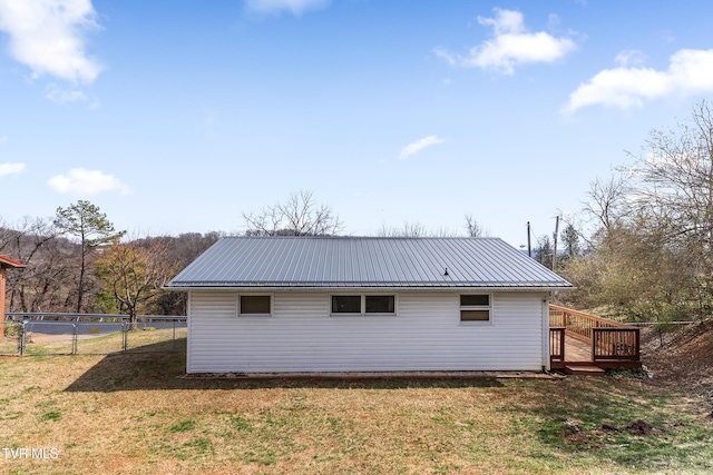 exterior space with metal roof, a yard, a deck, and fence