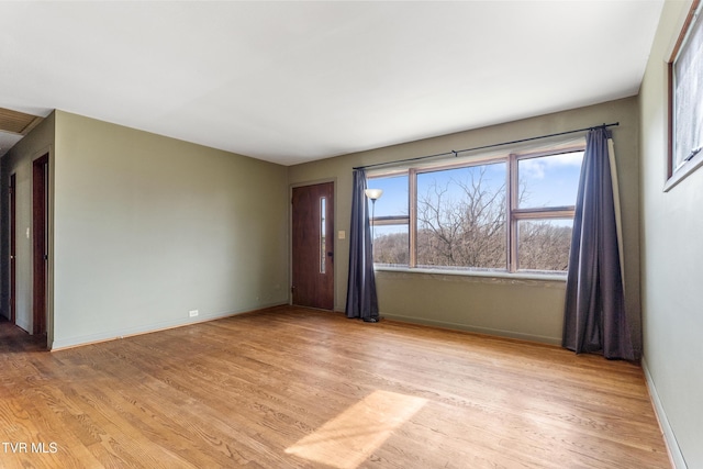 unfurnished room featuring baseboards and light wood finished floors