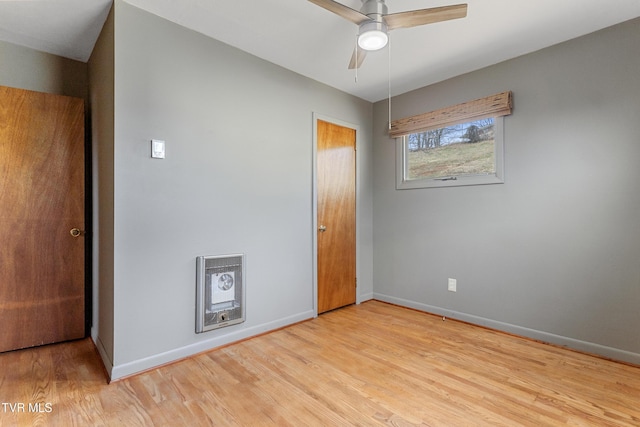 unfurnished bedroom featuring heating unit, light wood-style floors, and baseboards