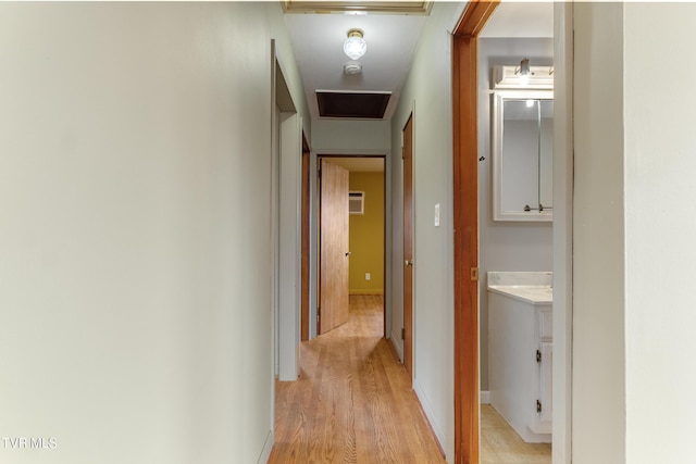 corridor featuring an AC wall unit, light wood-style floors, and baseboards