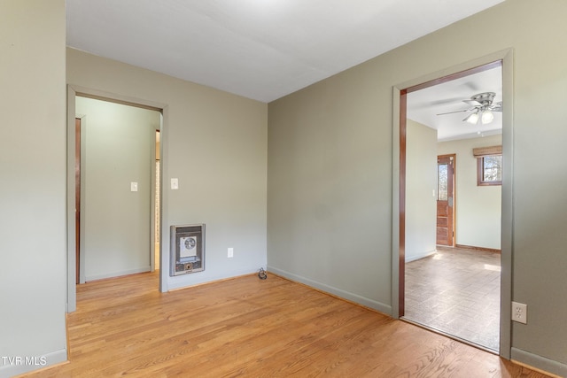 unfurnished room featuring light wood-type flooring, heating unit, baseboards, and ceiling fan