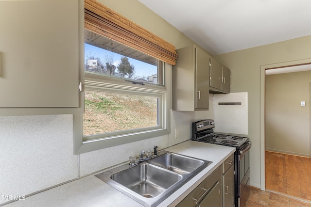 kitchen featuring baseboards, electric range, gray cabinets, a sink, and light countertops