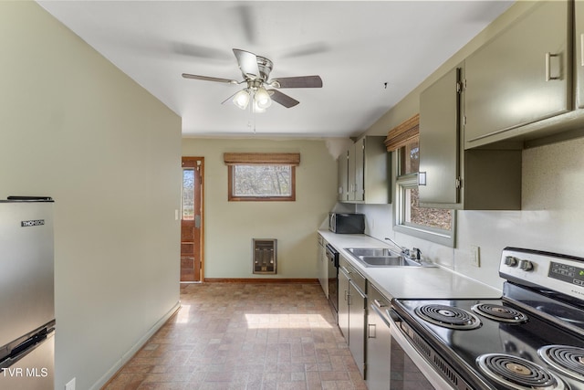 kitchen with a sink, stainless steel appliances, light countertops, baseboards, and ceiling fan