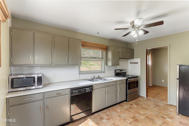 kitchen featuring a ceiling fan, a sink, gray cabinetry, light countertops, and appliances with stainless steel finishes