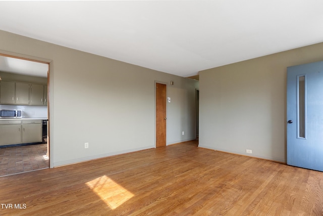 spare room with light wood-type flooring and baseboards