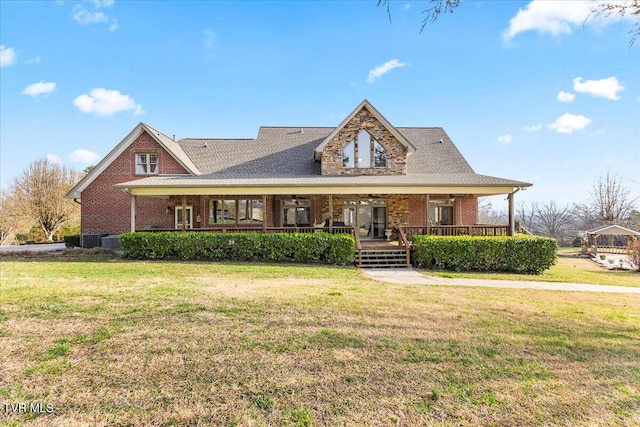 view of front of home featuring brick siding, covered porch, a ceiling fan, and a front yard