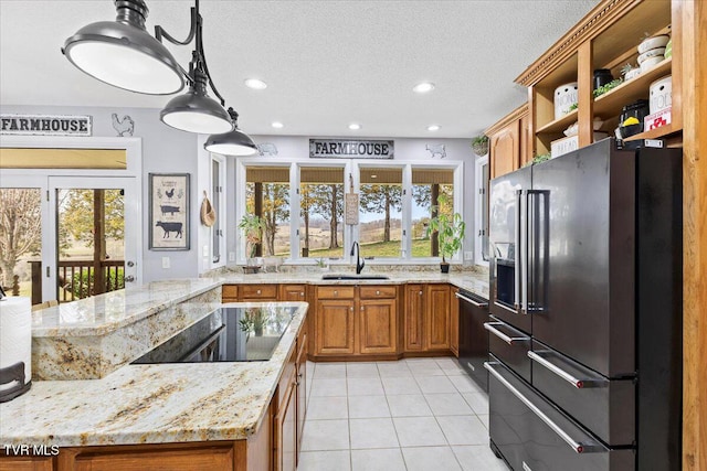 kitchen with a sink, french doors, high end refrigerator, black electric stovetop, and brown cabinets