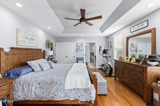 bedroom featuring a tray ceiling, recessed lighting, light wood-type flooring, and ceiling fan