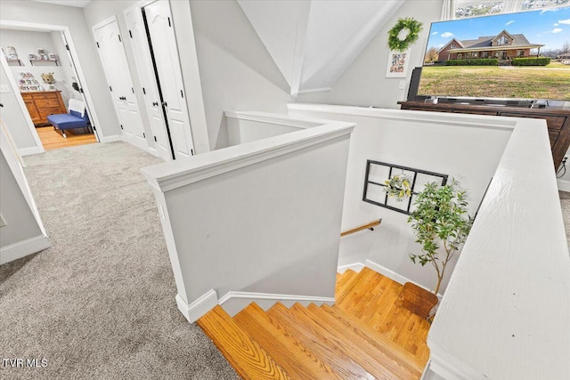 stairway featuring baseboards, carpet flooring, and vaulted ceiling