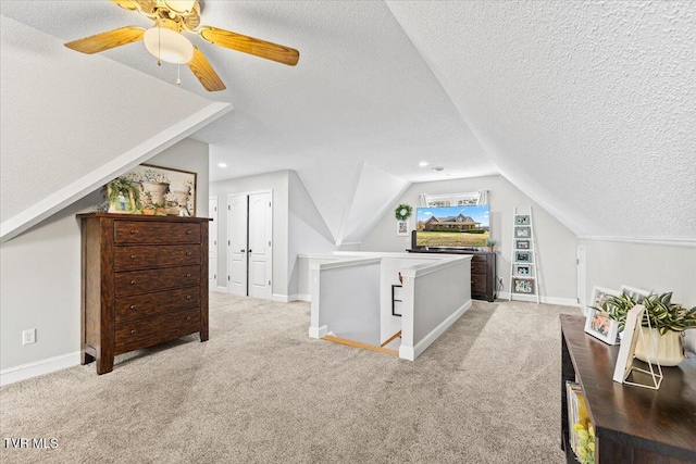 bedroom featuring a ceiling fan, baseboards, carpet floors, vaulted ceiling, and a textured ceiling