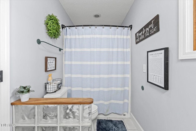 full bath featuring tile patterned floors, baseboards, a textured ceiling, and a shower with curtain