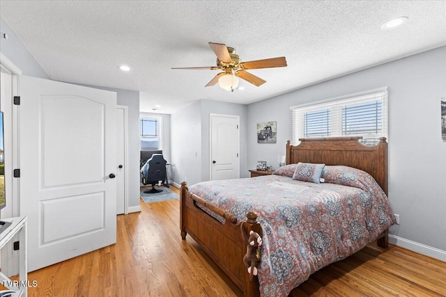 bedroom with baseboards, light wood-style floors, ceiling fan, and a textured ceiling