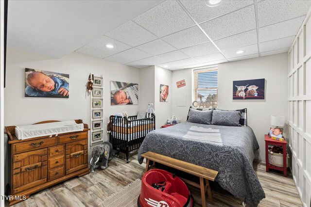 bedroom with recessed lighting, a paneled ceiling, and light wood finished floors