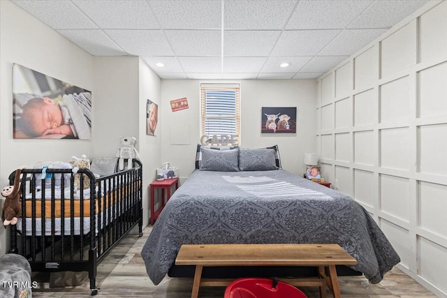 bedroom featuring recessed lighting, wood finished floors, and a paneled ceiling