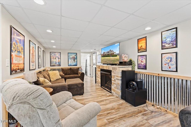 living room featuring recessed lighting, a drop ceiling, wood finished floors, and a fireplace